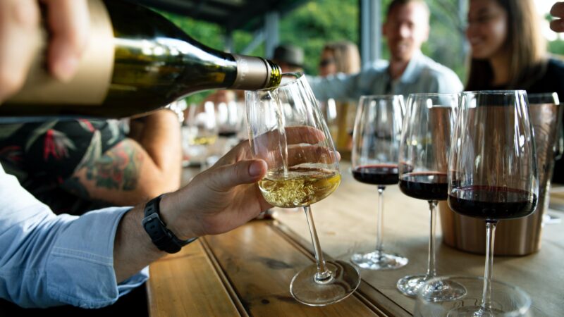 person pouring white wine into glass for holiday gifting